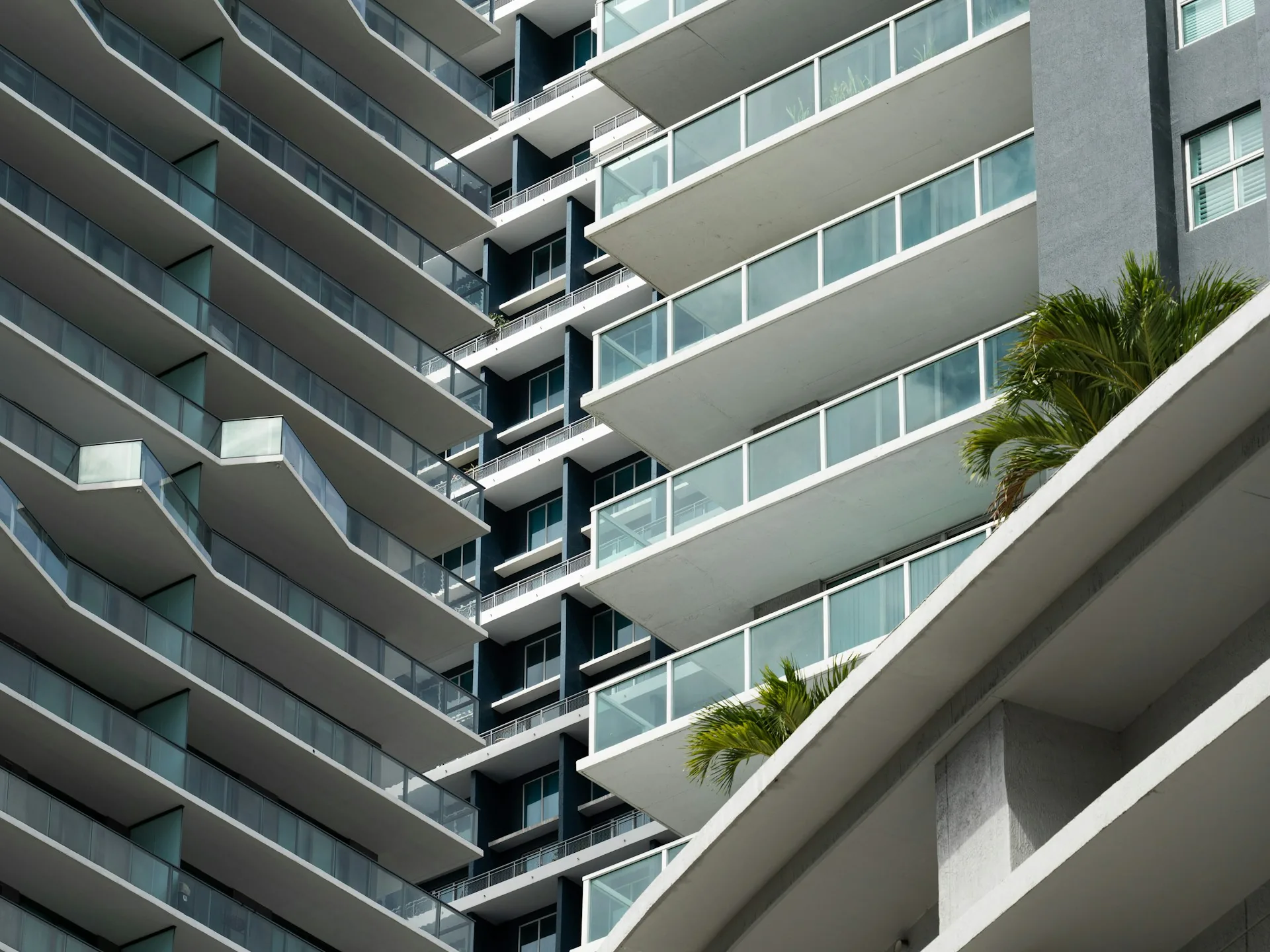 Apartment tower with glass balconies and palm trees